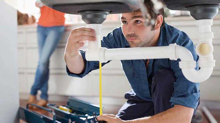 Man checking plumbing under a sink