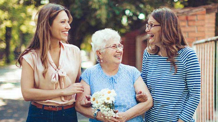 Three generations of women walking and talking about senior housing options.