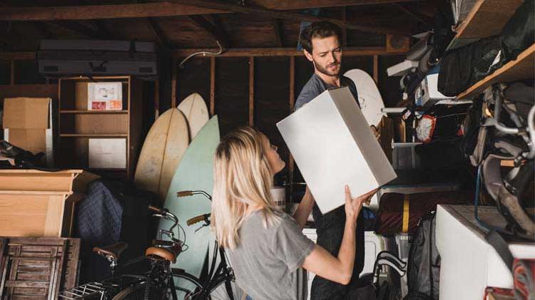 Woman handing man a box in garage for storage.